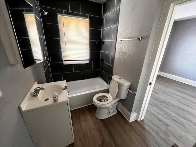 full bathroom with toilet, wood-type flooring, vanity, and tiled shower / bath