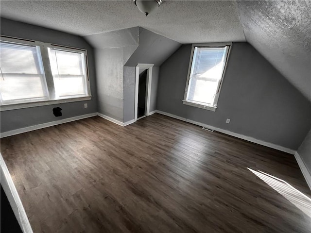 bonus room featuring a textured ceiling, vaulted ceiling, and dark hardwood / wood-style floors