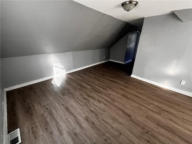 bonus room with dark hardwood / wood-style flooring, a textured ceiling, and vaulted ceiling