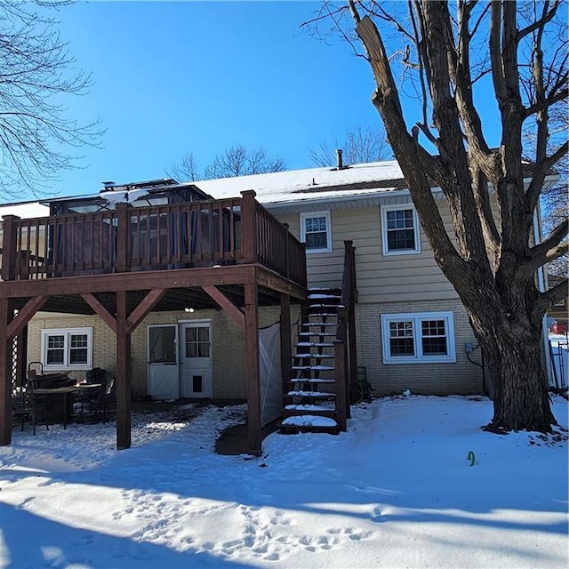 snow covered rear of property featuring a deck