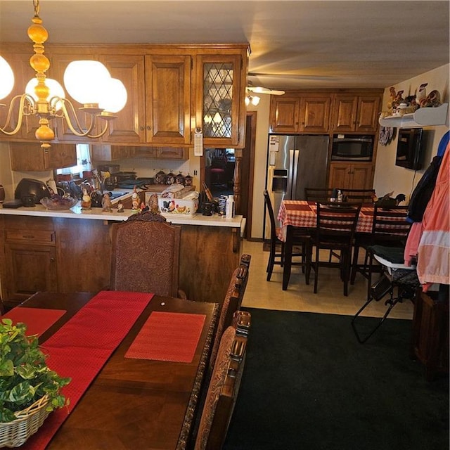 kitchen featuring kitchen peninsula, pendant lighting, stainless steel appliances, light tile patterned floors, and ceiling fan with notable chandelier