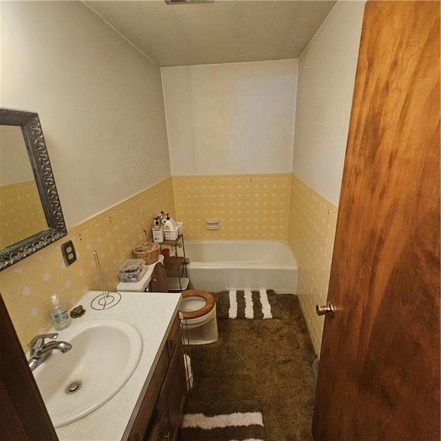 bathroom with a tub to relax in, vanity, and toilet