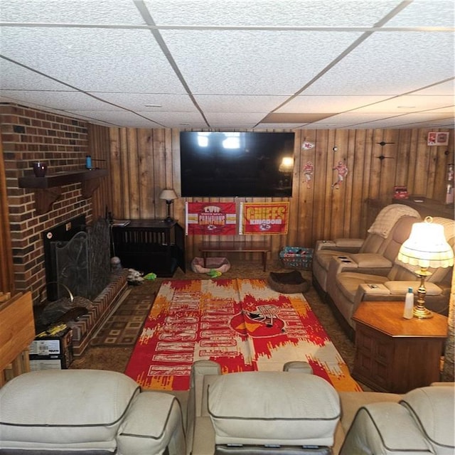 living room with a fireplace, wood walls, and a paneled ceiling