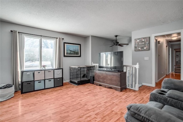 living room featuring a textured ceiling, ceiling fan, and light hardwood / wood-style floors