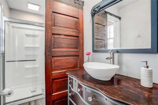 bathroom with toilet, wood-type flooring, vanity, and a shower with shower door