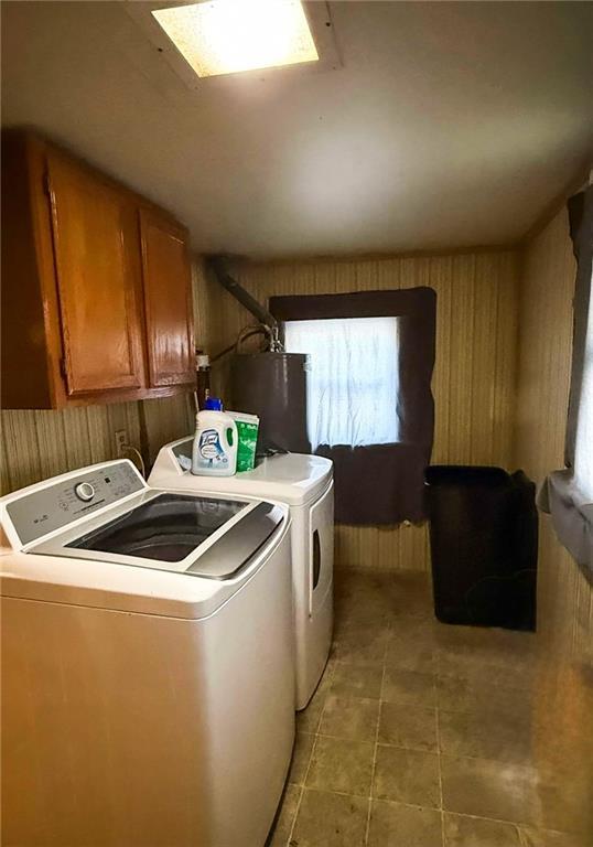 laundry room with water heater, a healthy amount of sunlight, cabinets, and washer and clothes dryer