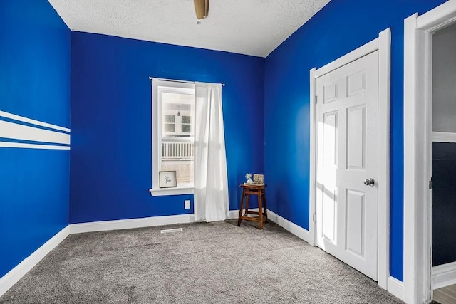 carpeted empty room featuring a textured ceiling