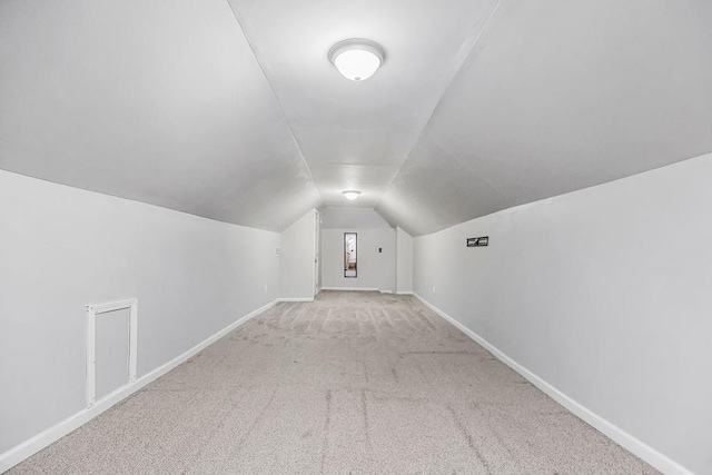 additional living space featuring lofted ceiling and light carpet