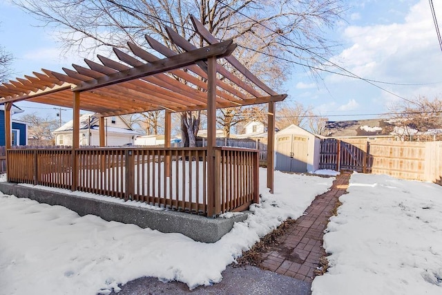 snow covered deck with a pergola and a shed