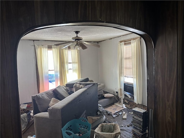 interior space with wooden walls, a textured ceiling, and ceiling fan