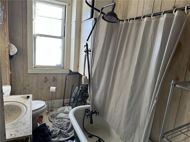 full bathroom with shower / bath combo with shower curtain, a wealth of natural light, wood walls, and toilet