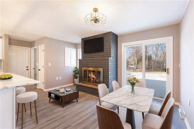 dining room featuring light hardwood / wood-style flooring, a fireplace, and a textured ceiling