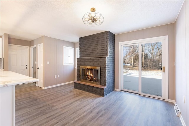 unfurnished living room featuring dark wood-type flooring, a brick fireplace, and a textured ceiling