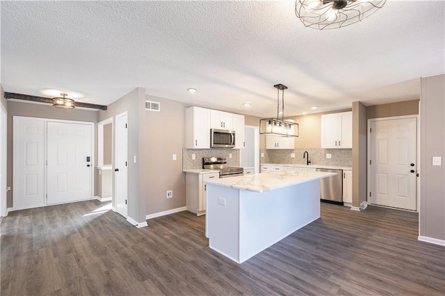 kitchen featuring decorative light fixtures, dark hardwood / wood-style flooring, a kitchen island, stainless steel appliances, and white cabinets