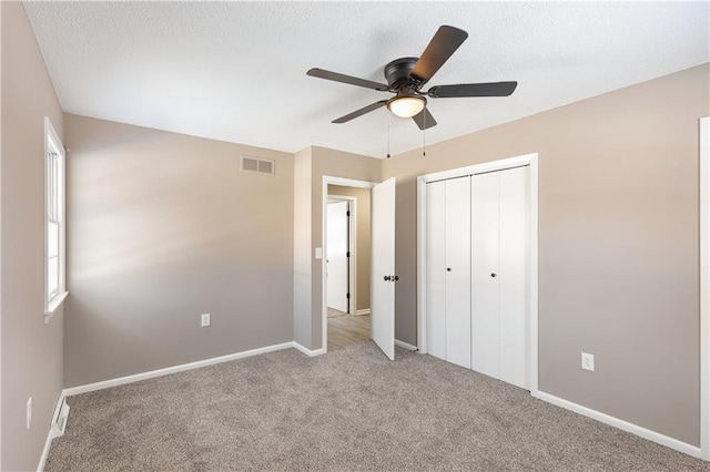 unfurnished bedroom with light colored carpet, a closet, and ceiling fan