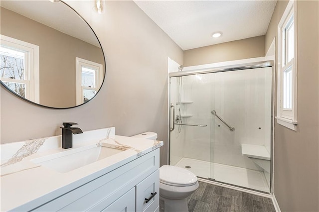 bathroom with an enclosed shower, vanity, hardwood / wood-style flooring, and toilet