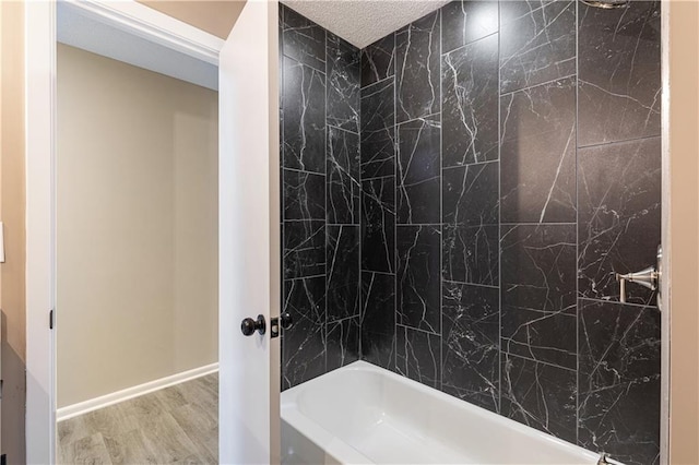 bathroom featuring hardwood / wood-style floors, shower / bathtub combination, and a textured ceiling