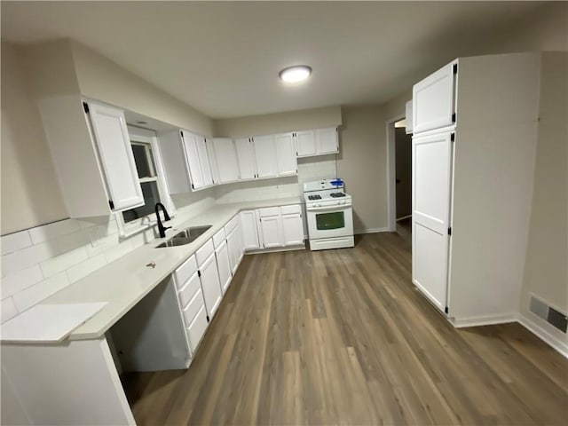 kitchen with dark wood-type flooring, sink, white cabinetry, white gas range, and backsplash