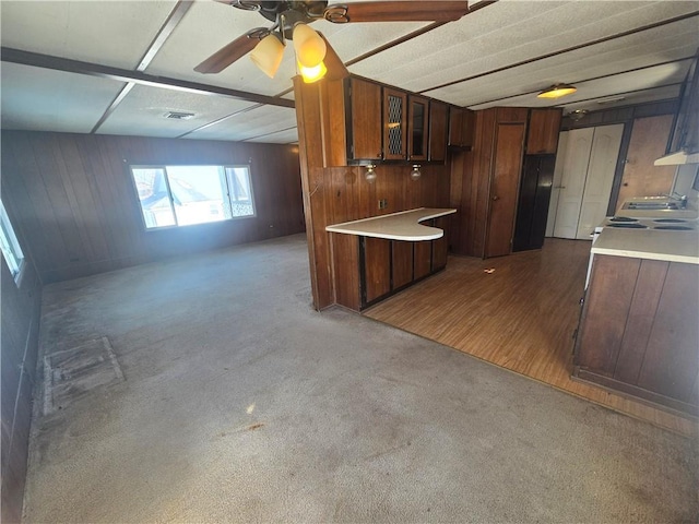 kitchen with ceiling fan, wooden walls, and dark carpet