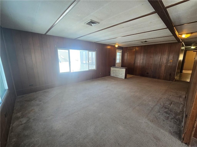 spare room with carpet floors and wood walls