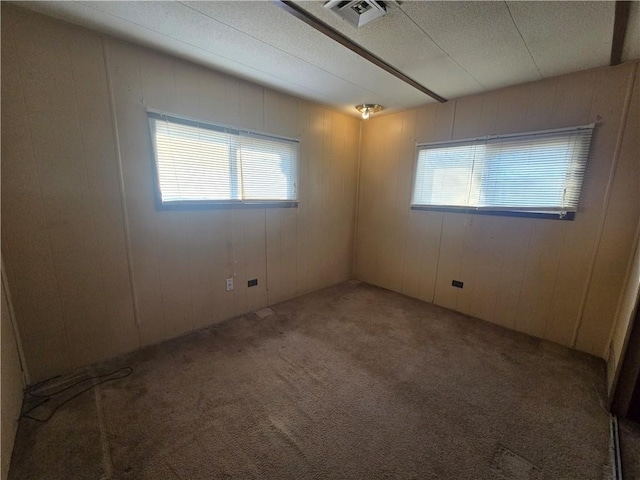 carpeted spare room with wooden walls