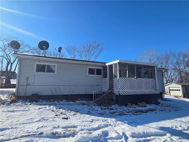 snow covered back of property with a sunroom