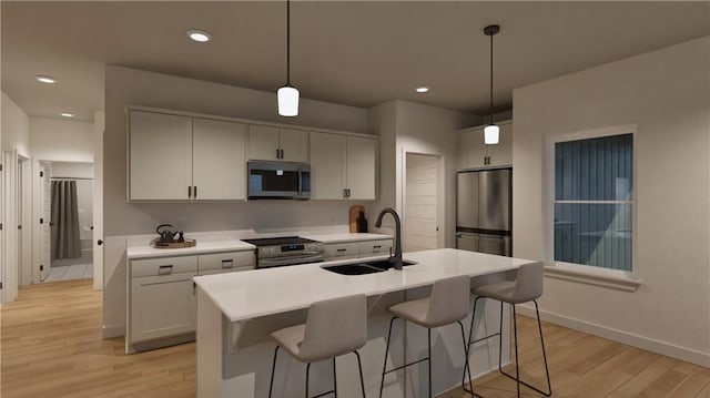 kitchen with decorative light fixtures, sink, a center island with sink, and stainless steel appliances