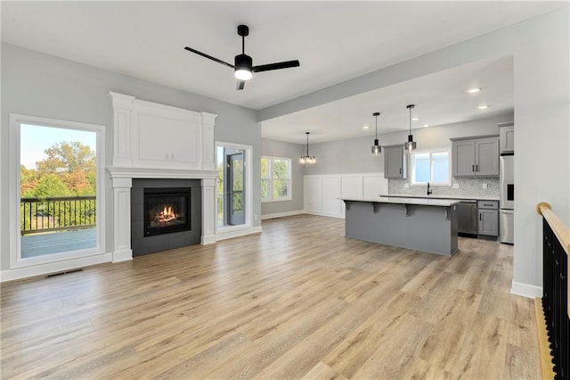 kitchen featuring a center island, decorative backsplash, gray cabinetry, a breakfast bar area, and ceiling fan