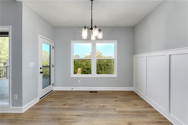 unfurnished dining area featuring light hardwood / wood-style floors and a chandelier