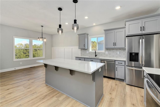 kitchen with sink, gray cabinets, a chandelier, pendant lighting, and appliances with stainless steel finishes