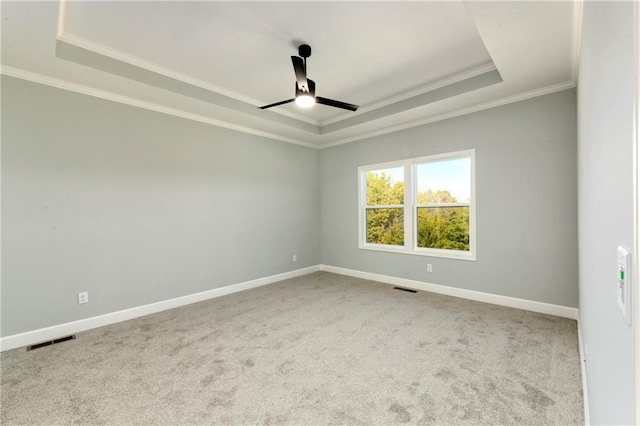 carpeted spare room with ceiling fan, crown molding, and a raised ceiling