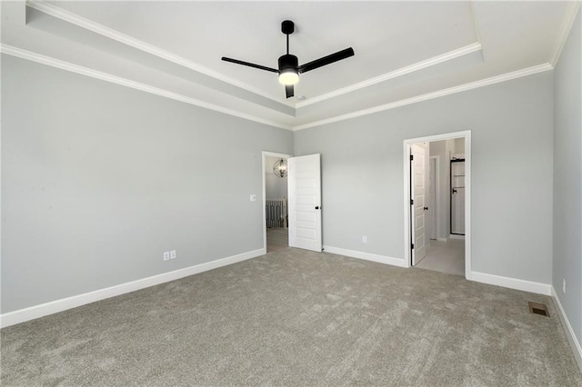 unfurnished bedroom featuring a raised ceiling, connected bathroom, ceiling fan, crown molding, and light colored carpet