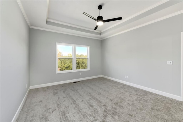 spare room with ornamental molding, ceiling fan, light colored carpet, and a tray ceiling