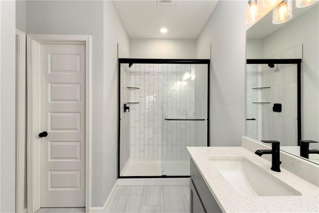 bathroom with a shower with door and vanity