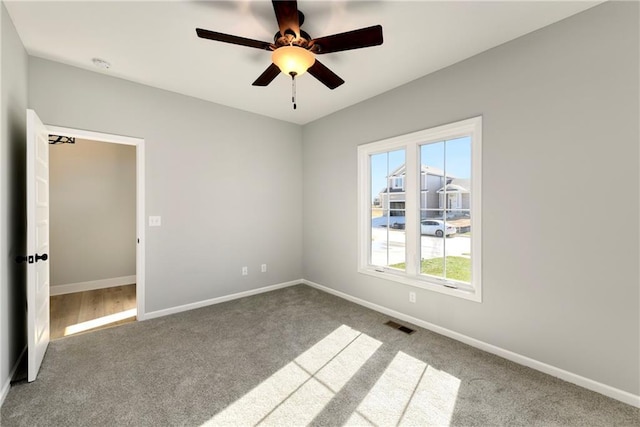 carpeted spare room featuring ceiling fan