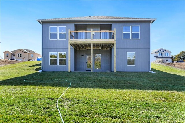 rear view of house featuring a balcony and a yard