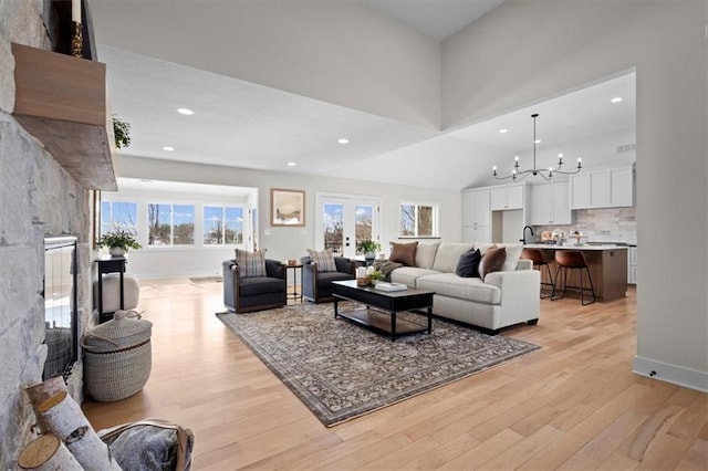 living room with light hardwood / wood-style floors, an inviting chandelier, and sink