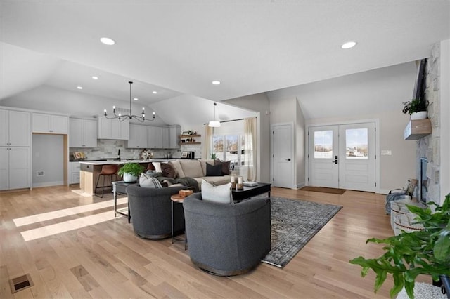 living room featuring high vaulted ceiling, light wood-type flooring, and a chandelier