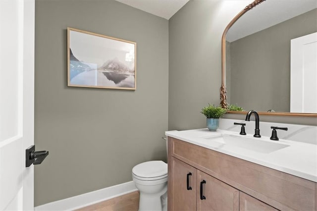 bathroom featuring wood-type flooring, vanity, and toilet