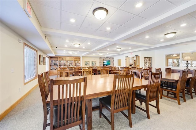 dining room featuring beamed ceiling and light carpet