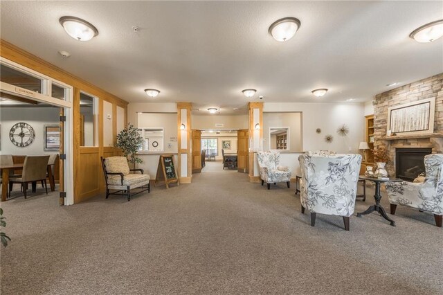 carpeted living room with a stone fireplace