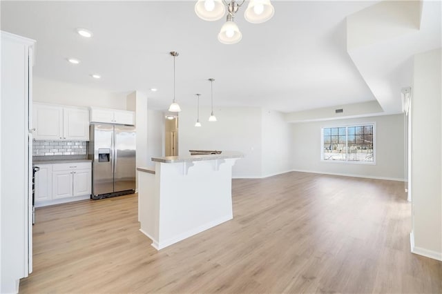 kitchen featuring decorative light fixtures, white cabinetry, a kitchen breakfast bar, decorative backsplash, and stainless steel refrigerator with ice dispenser