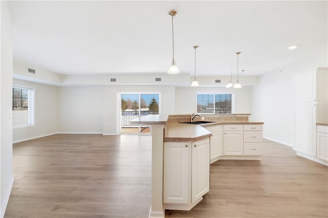 kitchen featuring pendant lighting, sink, a center island with sink, and plenty of natural light