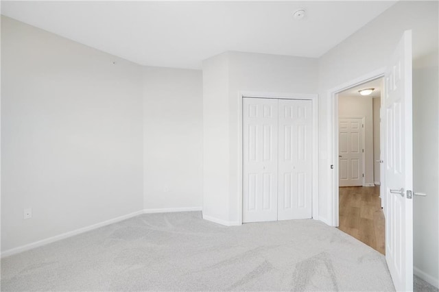 unfurnished bedroom with light colored carpet and a closet