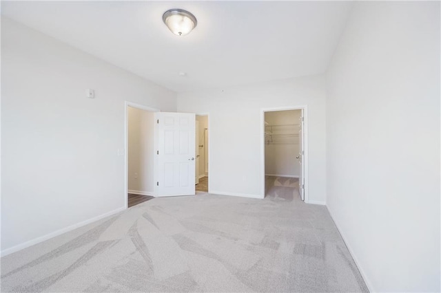 unfurnished bedroom featuring a walk in closet, light colored carpet, and a closet