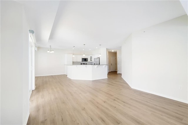 unfurnished living room featuring light hardwood / wood-style floors and a notable chandelier