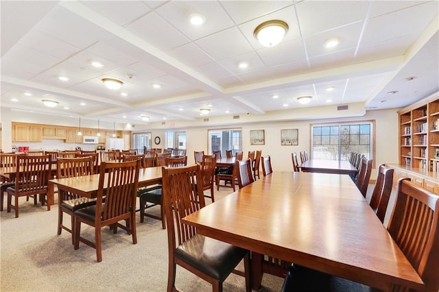 dining space featuring light carpet and beam ceiling