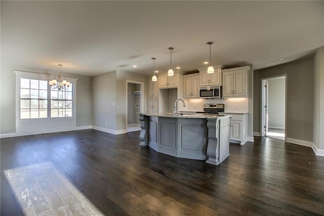 kitchen with baseboards, a chandelier, appliances with stainless steel finishes, dark wood-style floors, and a sink