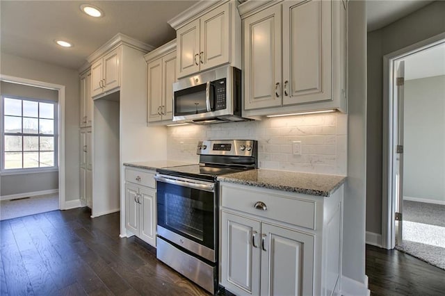 kitchen featuring decorative backsplash, appliances with stainless steel finishes, baseboards, and dark wood-style flooring