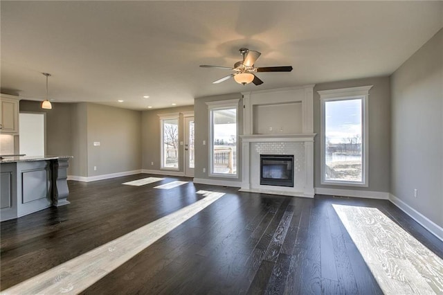 unfurnished living room with dark wood-type flooring, a fireplace with flush hearth, and baseboards